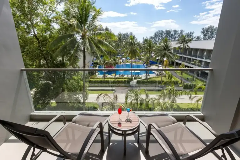 Balcony with lounge chairs at X10 Khaolak Resort in Khao Lak overlooking the pool, palm trees, and tropical grounds.