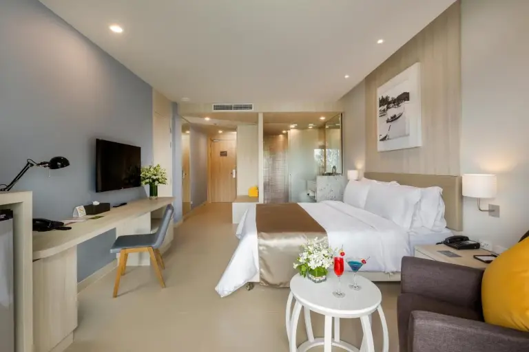 Modern guest room at X10 Khaolak Resort in Khao Lak with a bed, seating area, desk, and bathroom entrance.