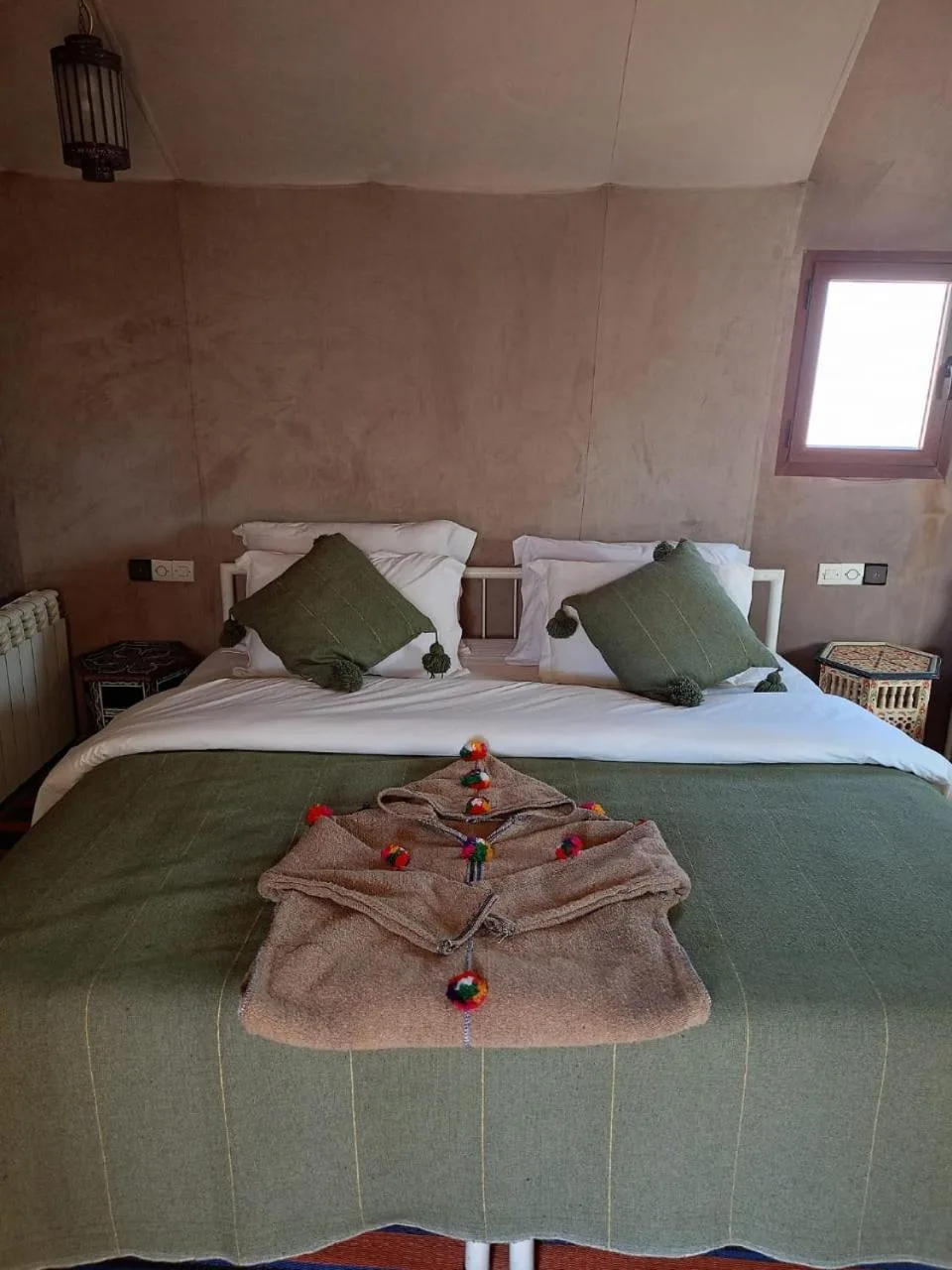 Double bed with green bedding and towels in a tent room at Zahra Luxury Desert Camp in Merzouga.