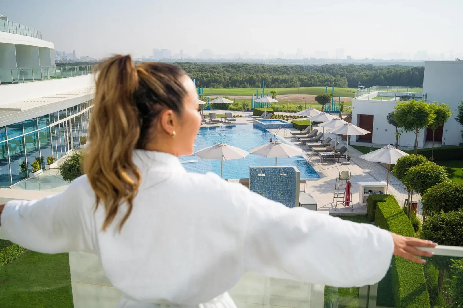 Guest enjoying the balcony view at Zoya Health & Wellbeing Resort in Ajman overlooking the pool and landscaped grounds