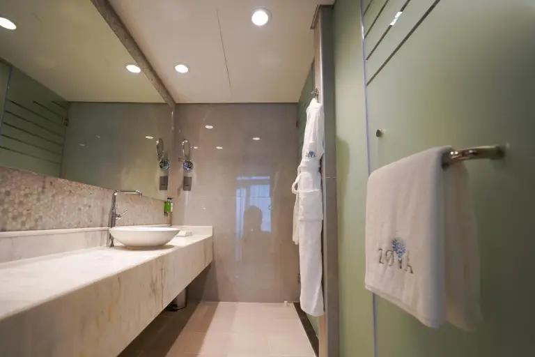 Contemporary bathroom at Zoya Health & Wellbeing Resort in Ajman with double vanity, glass shower, and bath amenities