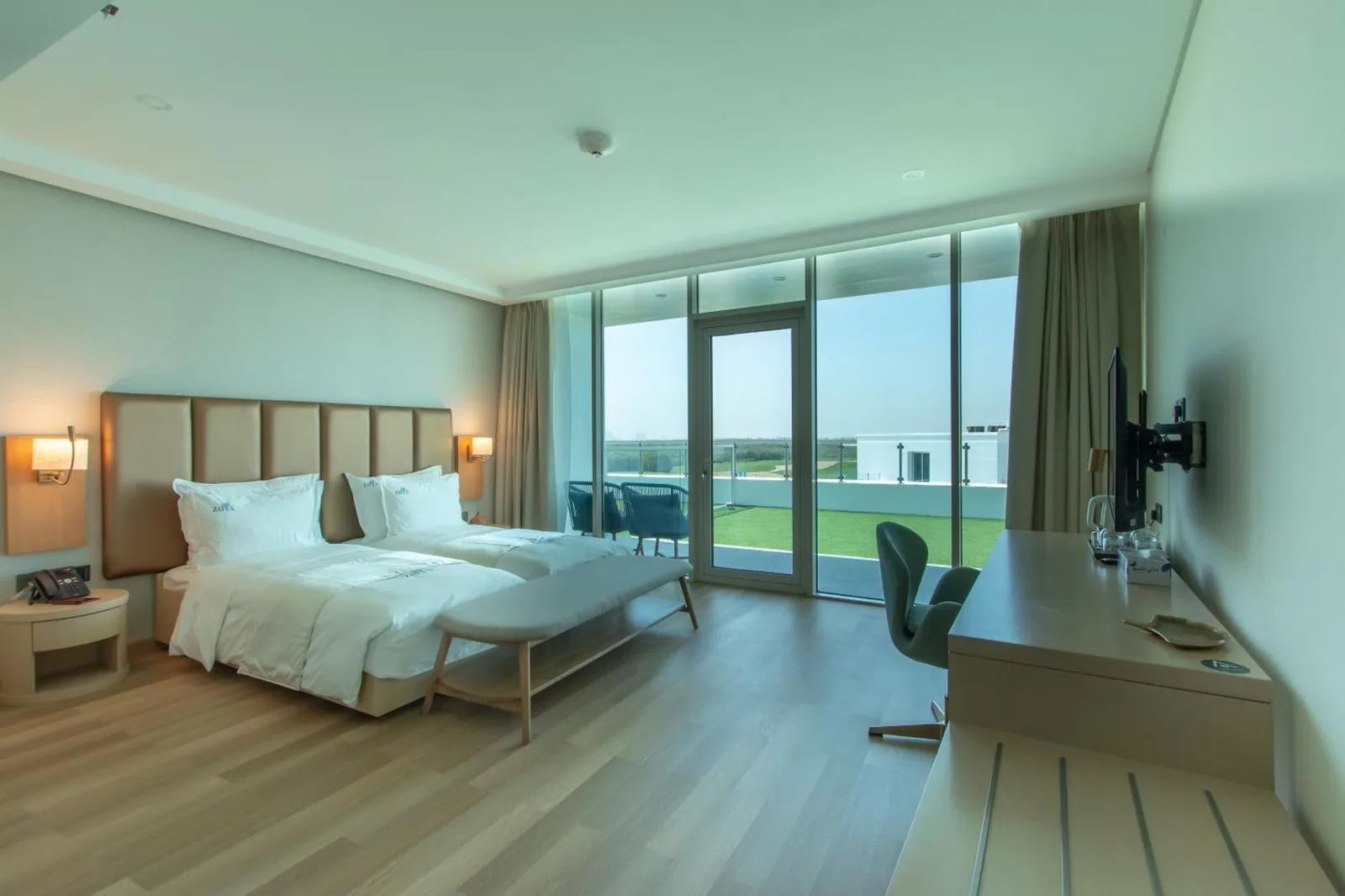Modern bedroom at Zoya Health & Wellbeing Resort in Ajman with twin beds, desk, and large windows