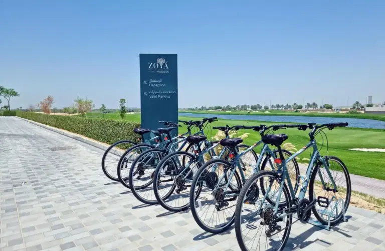 Bicycles parked outside Zoya Health & Wellbeing Resort in Ajman near the landscaped path and lake