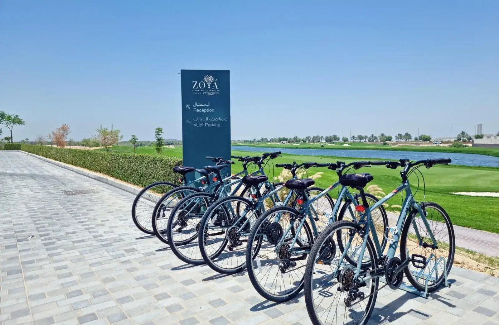 Bicycles parked outside Zoya Health & Wellbeing Resort in Ajman near the landscaped path and lake