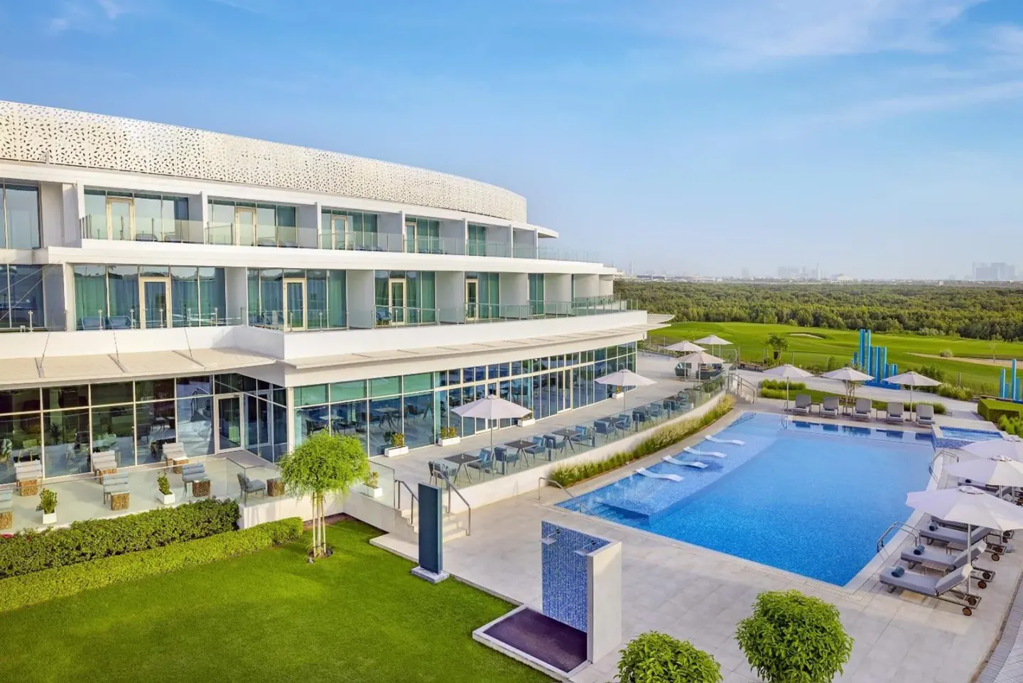 Exterior view of Zoya Health & Wellbeing Resort in Ajman with the outdoor swimming pool and modern hotel building